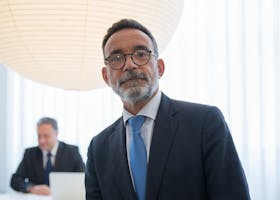 Confident senior executive in formal attire with modern office background.